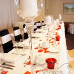 Set-up of Head Table, with Red Petals, Red Candles Holders, and Tall Stemmed Glass Candle Holders