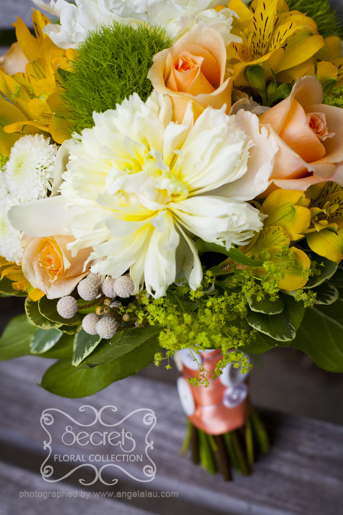 Fresh white peonies, peach roses, yellow alstroemeria, green trick dianthus, lady's mantle, white button mums (ice caps), and silver brunia berries bridal bouquet, with a peach ribbon and white buttons wrap (top-view) - Toronto Wedding Flowers by Secrets Floral Collection