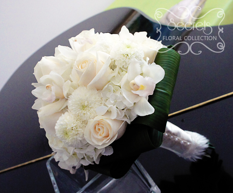 Fresh white cymbidium orchids, cream roses, white ice cap button mums, and cream hydrangea bridal bouquet, with white fur trim wrap (side-view) - Toronto Wedding Flowers by Secrets Floral Collection