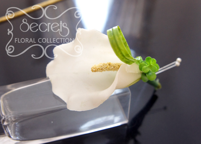 Artificial white calla lily boutonniere with boxwood leaves, lily grass, and double pearl pins (top-view) - Toronto Wedding Flowers Created by Secrets Floral Collection