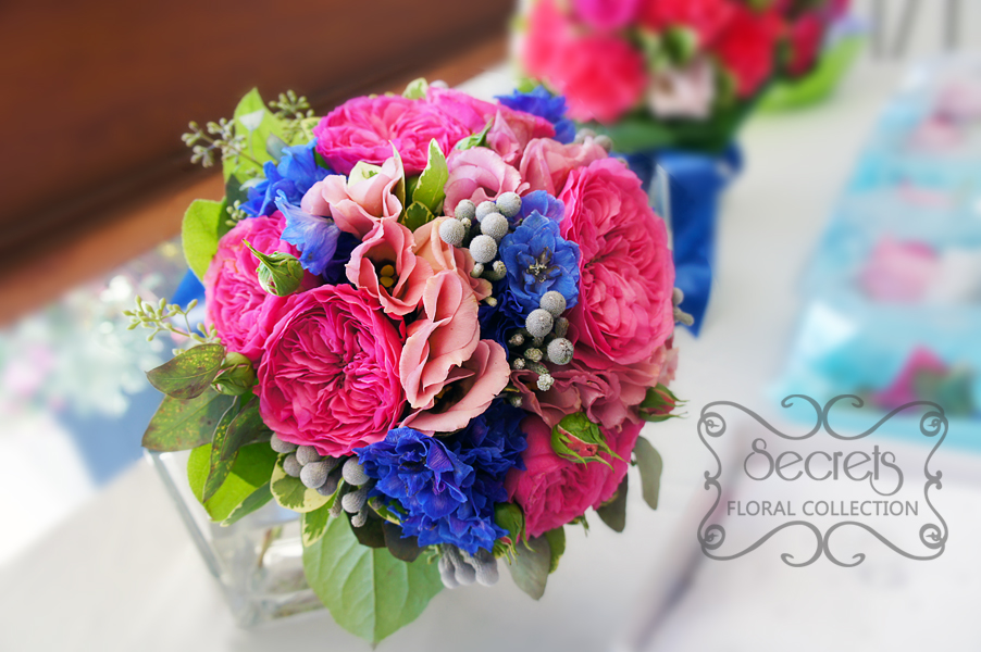 Fresh fuchsia garden roses, medium pink lisianthus,dark blue delphinium, silver brunia berries, and green seeded eucalyptus bridal bouquet, with a royal blue and sparkly mesh wrap (top-view) - Toronto Wedding Flowers by Secrets Floral Collection
