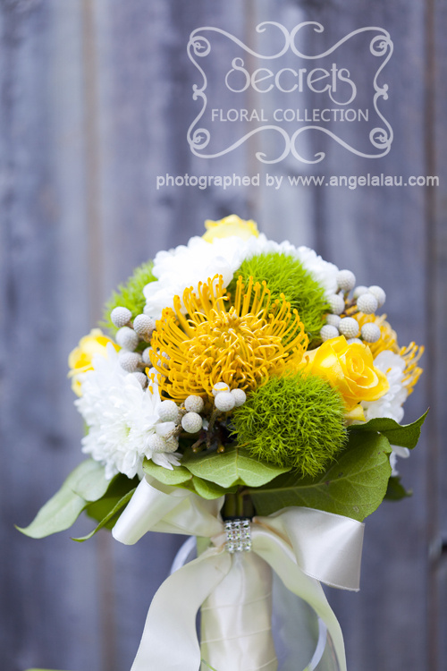 Fresh yellow roses, yellow protea pin cushions, white mums, green trick dianthus, and silver brunia berries spring theme bridal bouquet (front view) - Toronto Wedding Flowers by Secrets Floral Collection