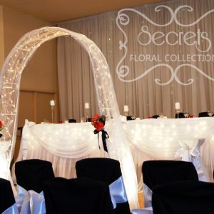 Backdrop and Tables are Decorated with White Sheer and Twinkle Lights to Achieve a Fairytale Look