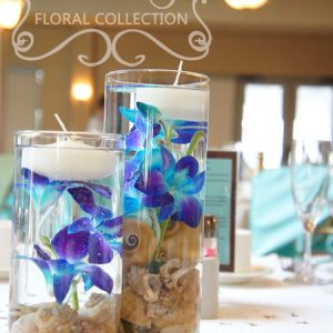 Close-up of centrepiece made with blue dendrobium orchid, seashells, and floating candles