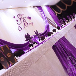 Head table decorated with white crinkled linen and purple satin stripes. Table edge is crystallized by adding our Bling! Bling! edge around the entire table