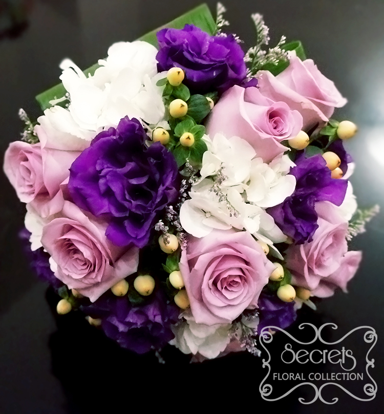 Fresh lavender roses, purple lisianthus, white hydrangea, ivory hypericum berries and misty blue limonium bridal bouquet, with ivory satin wrap with pearl and diamond brooch