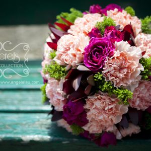 Fresh pink carnations, fuchsia spray roses, burgundy leucadendron, green trachelium bridal bouquet, embellished with ivory ribbon and gold crystal brooch (top view)