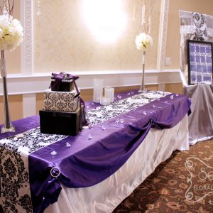 Receiving table with draped with purple overlay and damask runner. The easel is dressed up with damask fabric and crystal mesh ribbon - Toronto Wedding Decor Created by Secrets Floral Collection