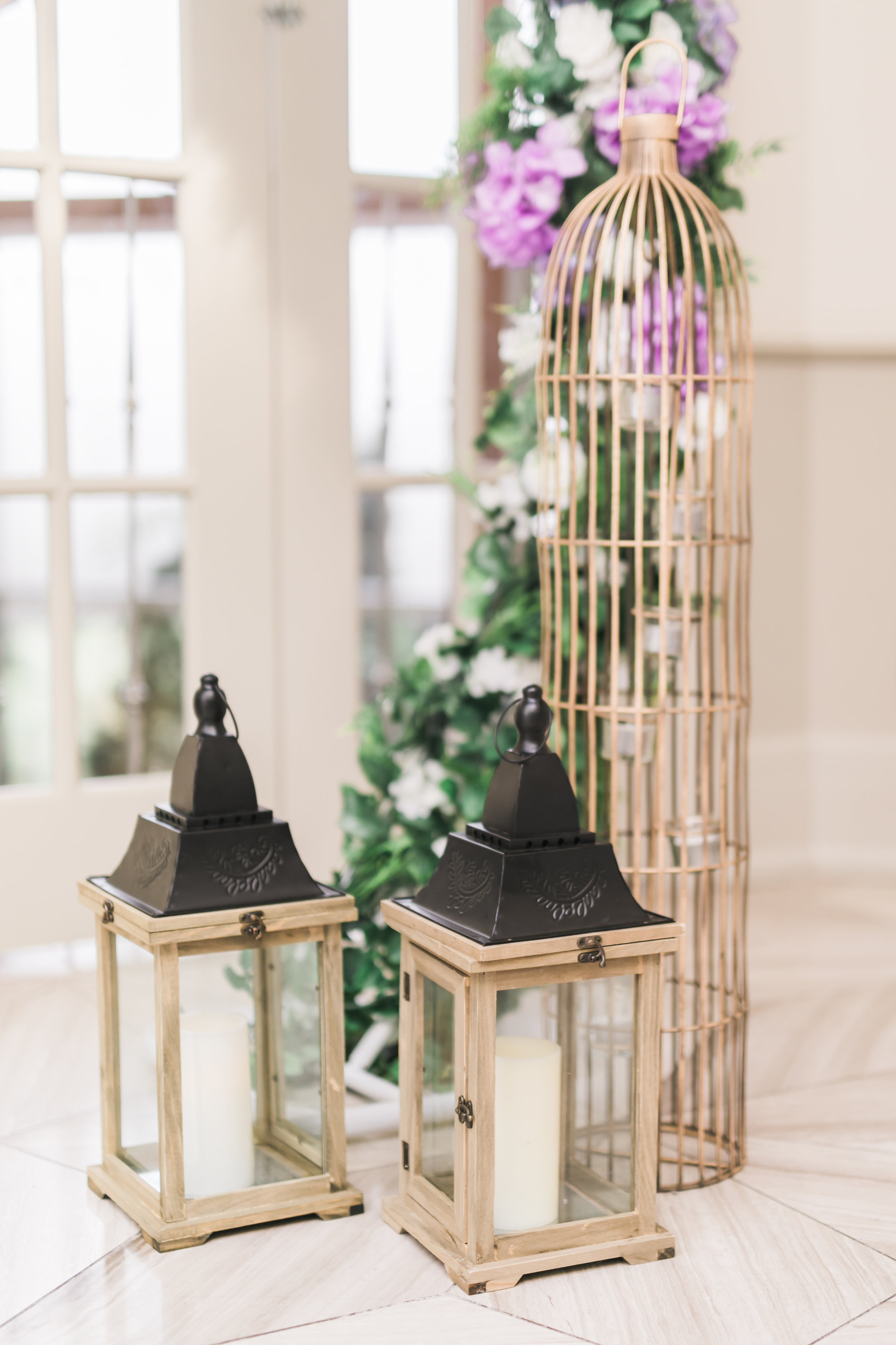 Rustic wood lantern and gold birdcage beside ceremony arch. Toronto wedding flowers and decor at Fontana Primavera by Secrets Floral.