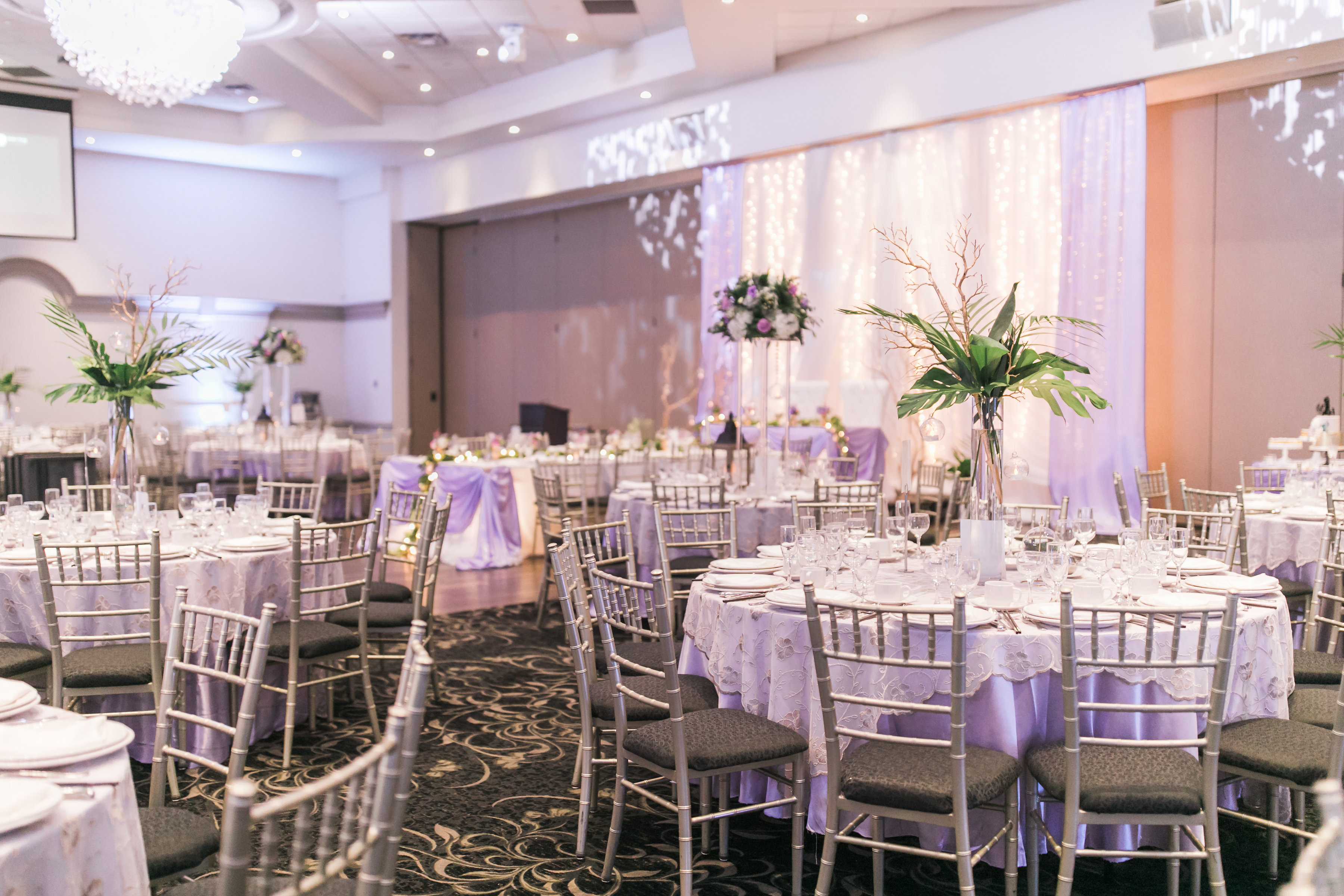 Wedding reception at Fontana Primavera, with tall centrepieces, purple tablecloths, and gold overlay linens. Toronto wedding flowers and decor by Secrets Floral.