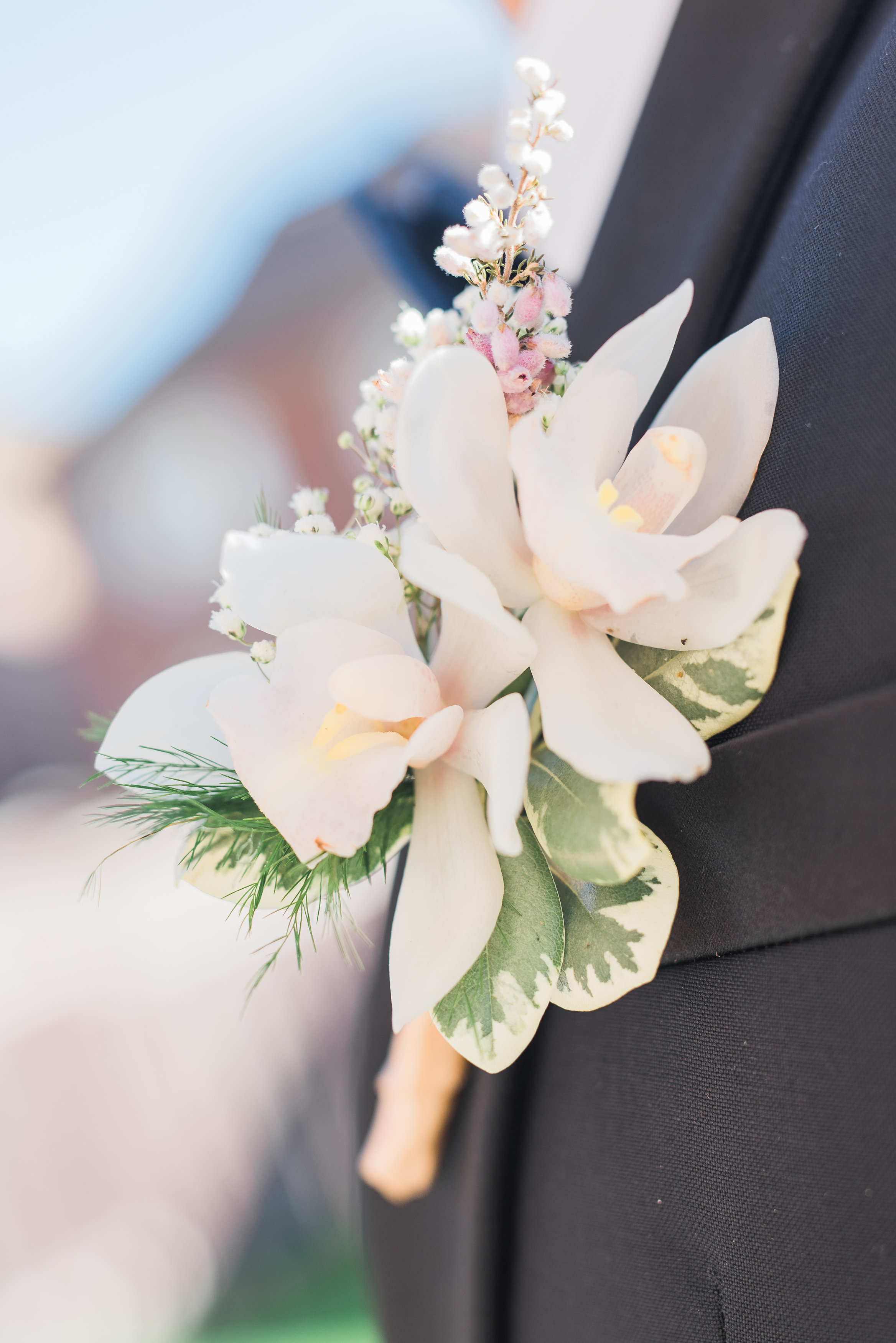 Groom boutonniere with white cymbidium orchids and pink heather flower. Toronto wedding flowers by Secrets Floral.