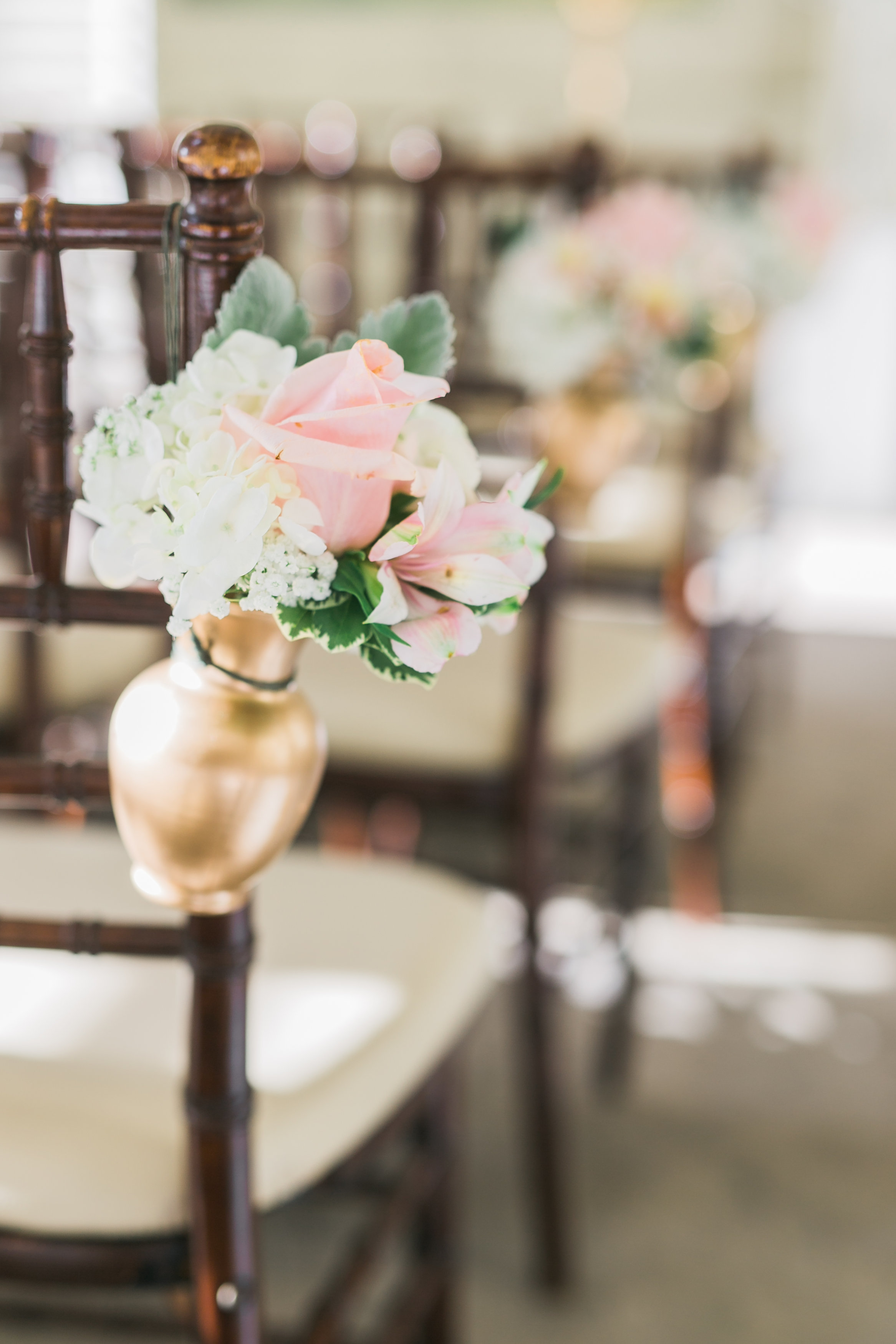 Fresh cream and blush pink wedding ceremony pew markers, with roses, hydrangea, and dusty miller in gold vases. Toronto wedding flowers by Secrets Floral.